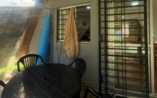 Barbacoa techada con mesa y sillas, junto a la puerta de la cabaña